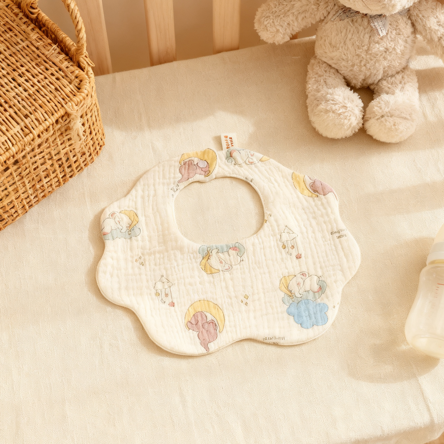 Baby bib with cartoon designs on a soft surface with toys in the background