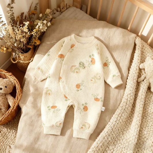 Baby romper with floral pattern on a crib with teddy bear and flowers.