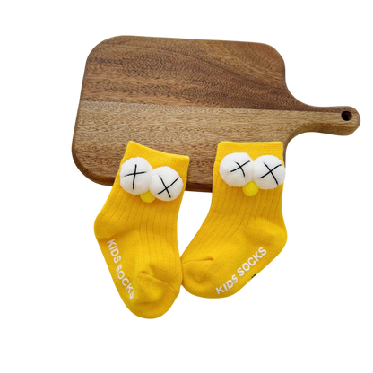 Yellow socks with cartoon face design on a wooden board