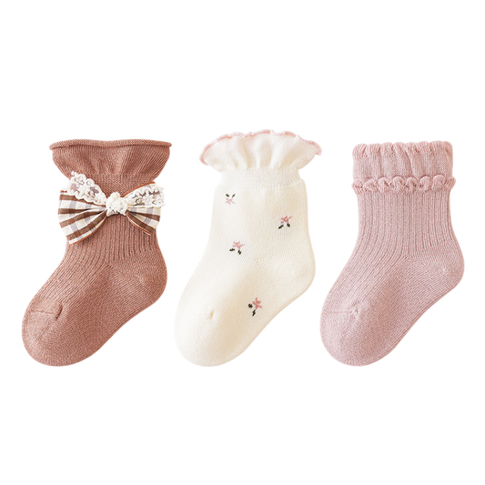 Three pairs of baby socks with decorative elements on a white background