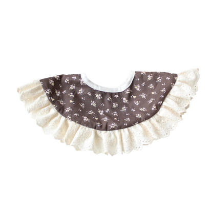 Baby bib with floral pattern and ruffled edge on a white background