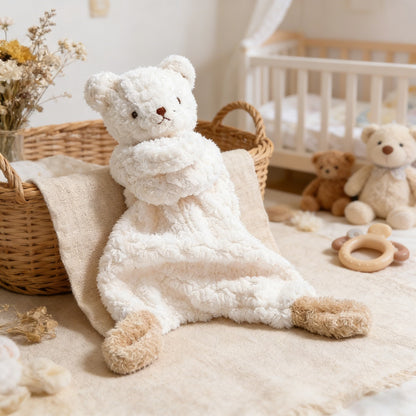 White teddy bear sitting on a soft surface with a crib and other toys in the background
