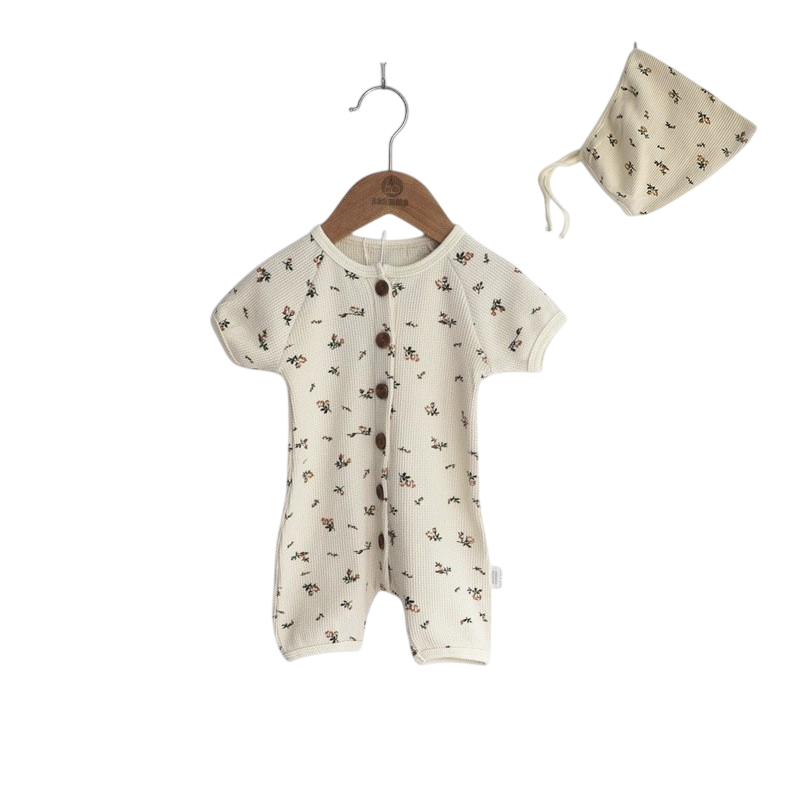Baby romper with floral pattern and matching hat on a white background