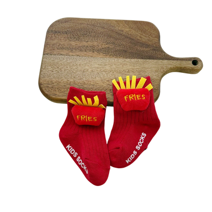 Red socks with 'Fries' design and 'Kids Socks' text on a wooden cutting board.