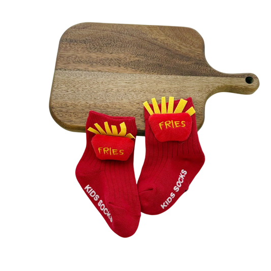 Red socks with 'Fries' design and 'Kids Socks' text on a wooden cutting board.