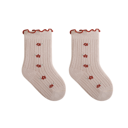 Pair of beige socks with red floral patterns and ruffled edges on a white background