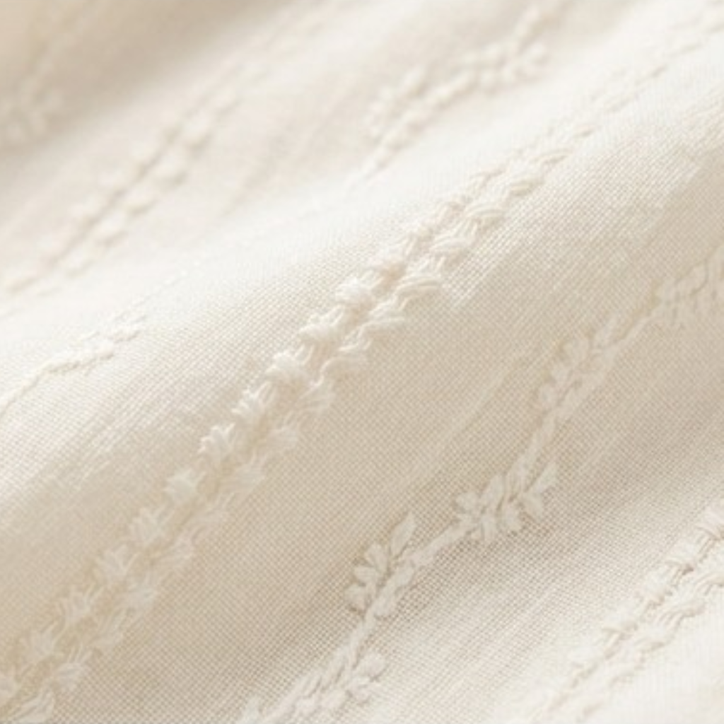 Close-up of textured cream fabric with vertical decorative stitching
