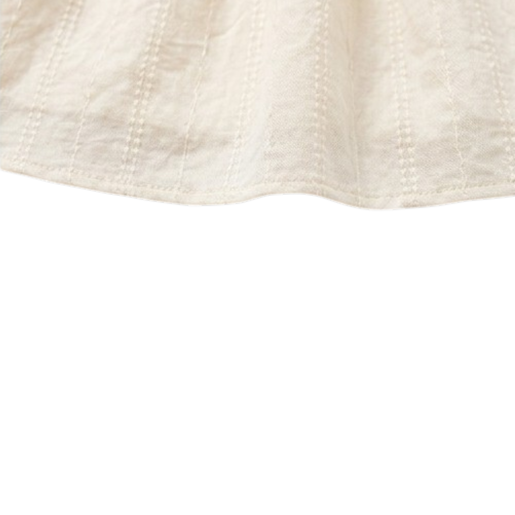 Close-up of the gathered hem on a cream girls dress