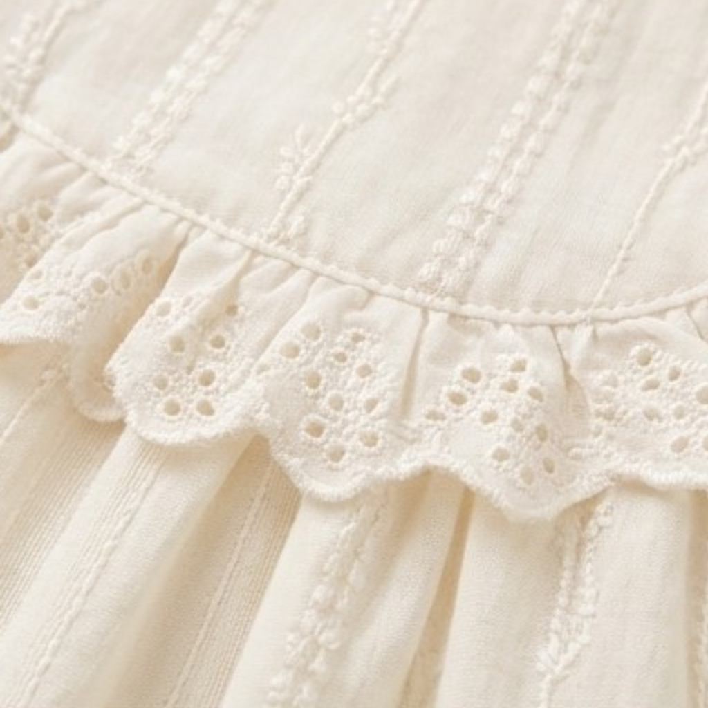 Close-up of eyelet lace ruffle trim on a cream dress
