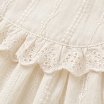 Close-up of eyelet lace ruffle trim on a cream dress