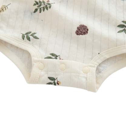 Close-up of the three-snap bottom closure on the cream botanical baby bodysuit