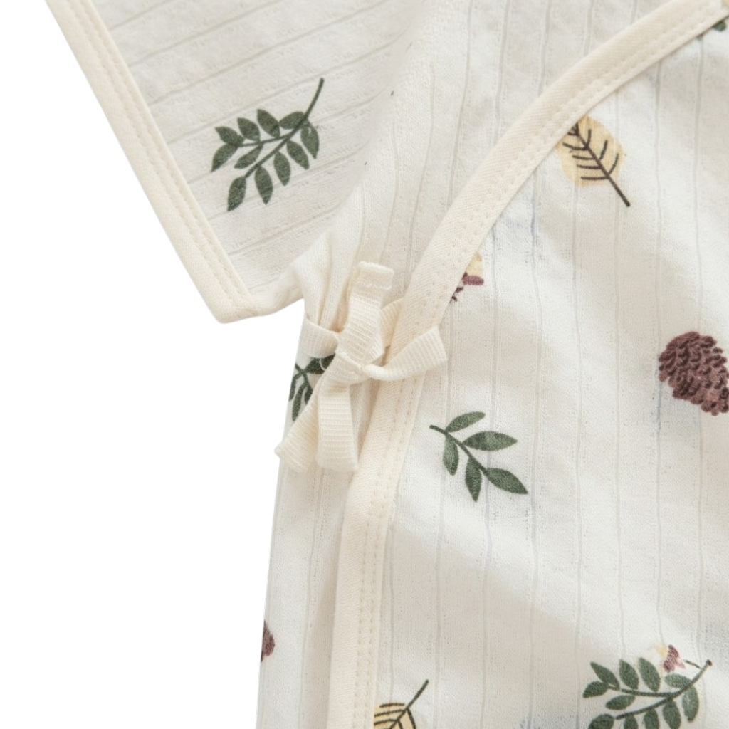 Close-up of the side-tie closure and cream trim on the botanical baby bodysuit