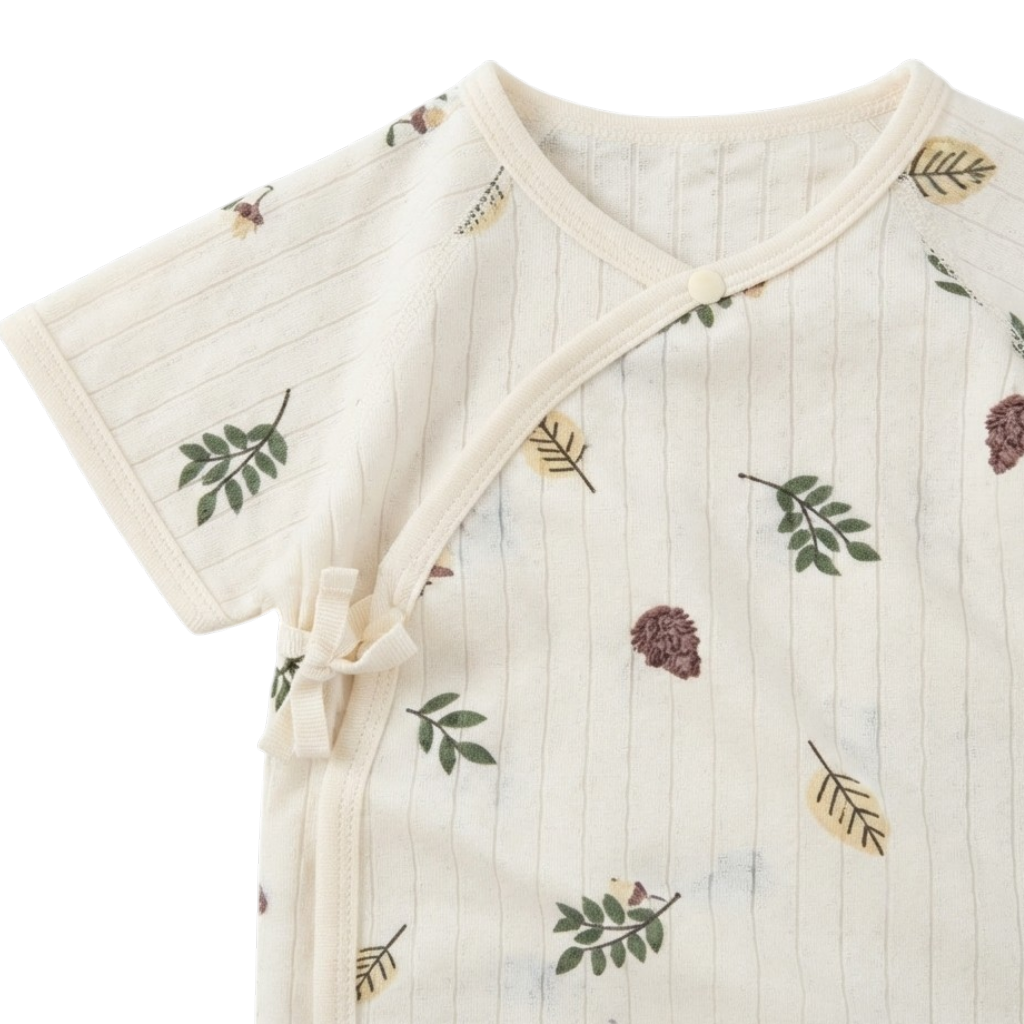 Close-up of the wrap neckline and side-tie closure on the cream baby bodysuit