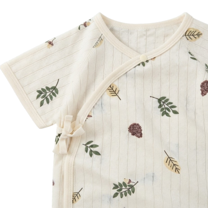 Close-up of the wrap neckline and side-tie closure on the cream baby bodysuit