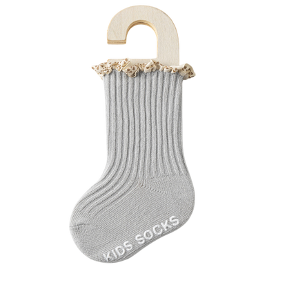 Gray kids' socks with beige trim on a wooden hanger against a white background
