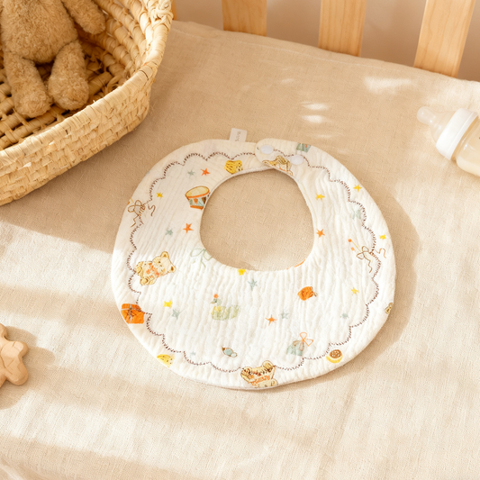 Baby bib with cartoon designs on a beige surface